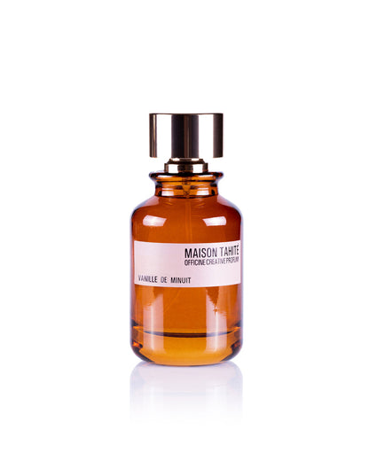 A brown glass bottle with a gold cap labeled "Maison Tahite Vanille de Minuit Eau de Parfum" displays this unisex vanilla fragrance by Maison Tahite against a plain white background.