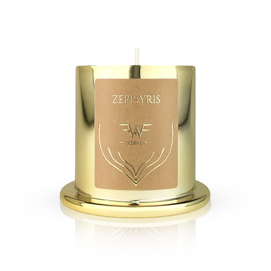 The Zephyris Candle by Wesker features a shiny gold holder with "Zephyris" and Wesker on its beige label, an embossed design, and a single wick. Inspired by Westwind, it sits on a matching gold base and evokes warm desert notes.