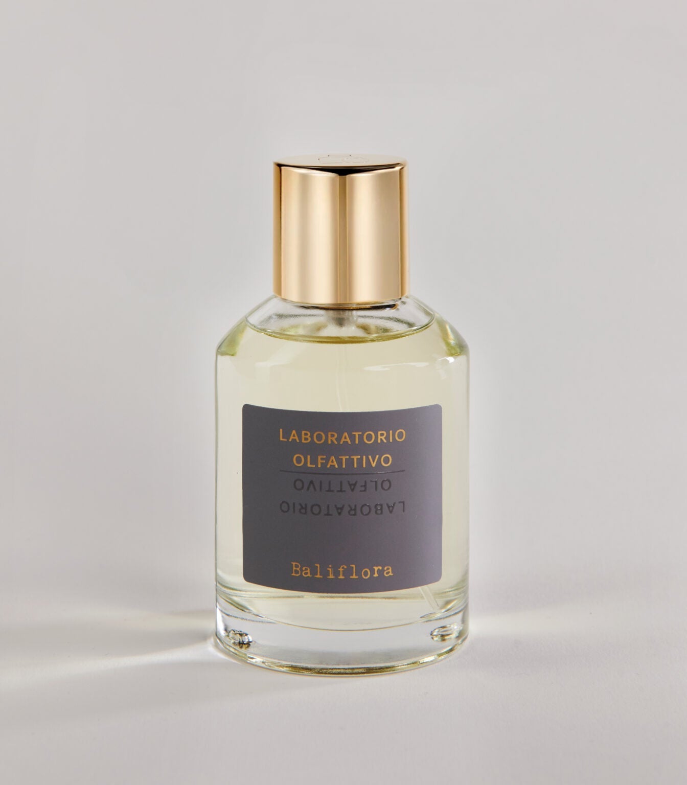 A clear glass bottle of Baliflora - Laboratorio Olfattivo TESTER with a gold cap and gray label, set against a light, neutral background.
