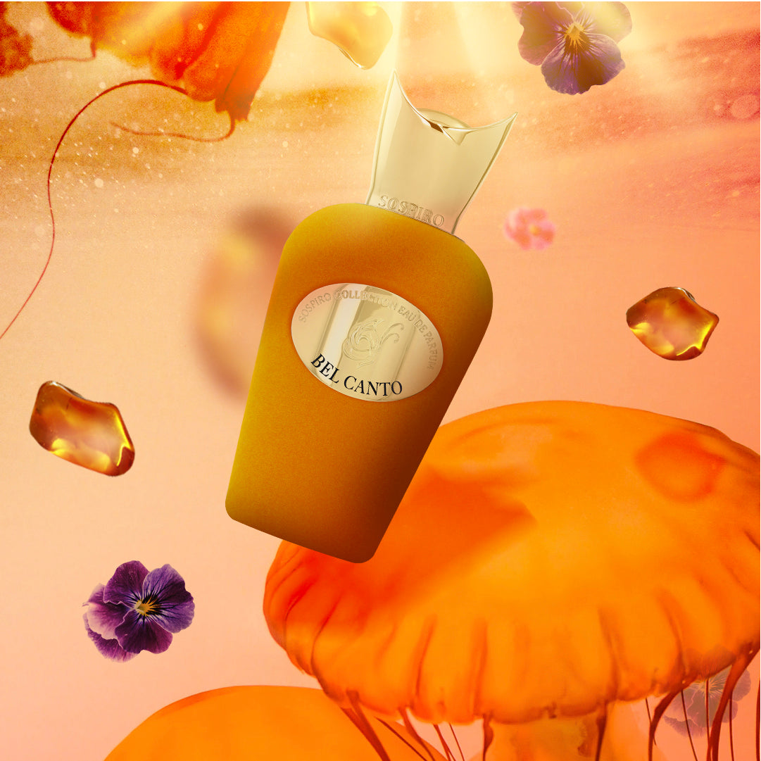 A floating golden Bel Canto Eau de Parfum by SOSPIRO appears among orange jellyfish, purple pansies, and amber droplets, suggesting a floral jasmine scent set against a warm, glowing backdrop.