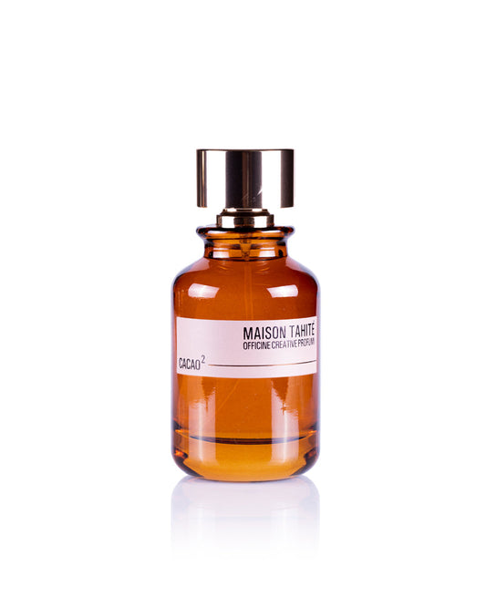 A brown glass bottle of Maison Tahite Cacao 2 Eau de Parfum, with a shiny gold cap and white label, is photographed on a white background, evoking an indulgent cocoa scent with extra dark chocolate notes.