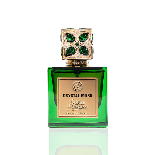A green glass bottle of Crystal Musk Eau de Parfum by Christian Provenzano features a jeweled gold and green cap, gold plaque branding, and blends musky amber with floral notes. The perfume is pictured on a white background.