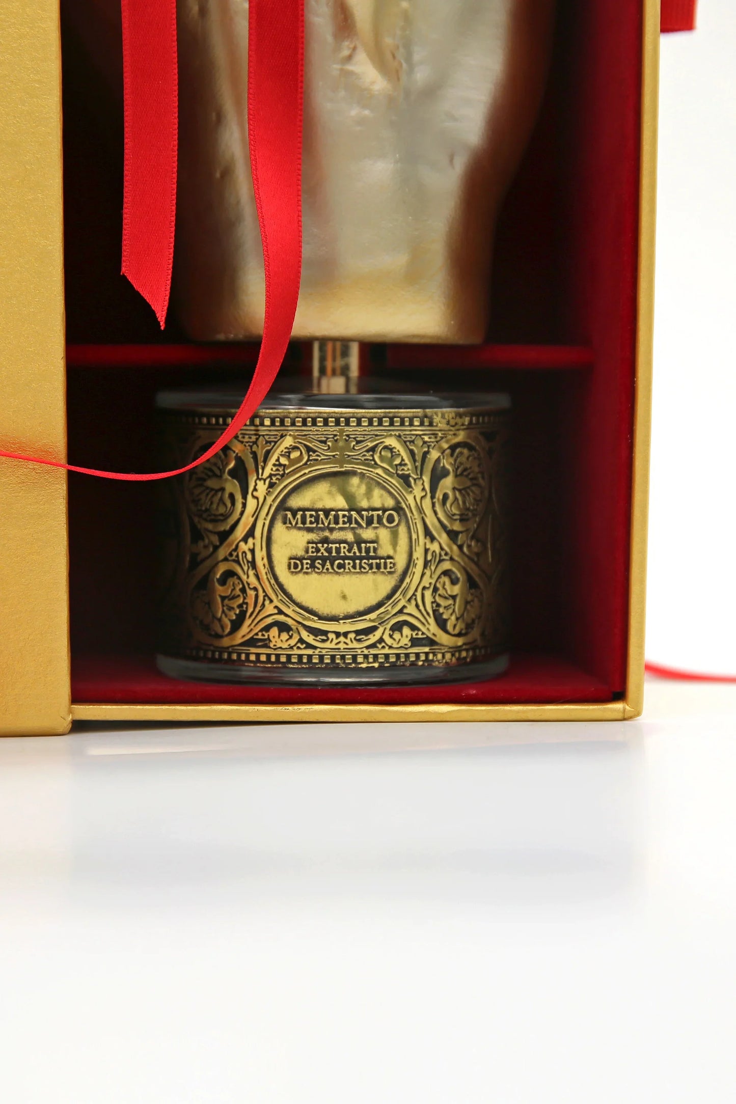 A luxurious gold and black bottle of PONT. MAX. Eau de Parfum by Filippo Sorcinelli, evoking amber and resin incense, sits partially inside an open gold box with red ribbon on a white surface.