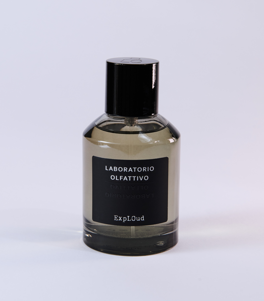 A clear glass bottle with a black cap and label reading "Laboratorio Olfattivo ExplOud Eau de Parfum" rests on a white background, emphasizing this woody, luxurious oud fragrance from Laboratorio Olfattivo.