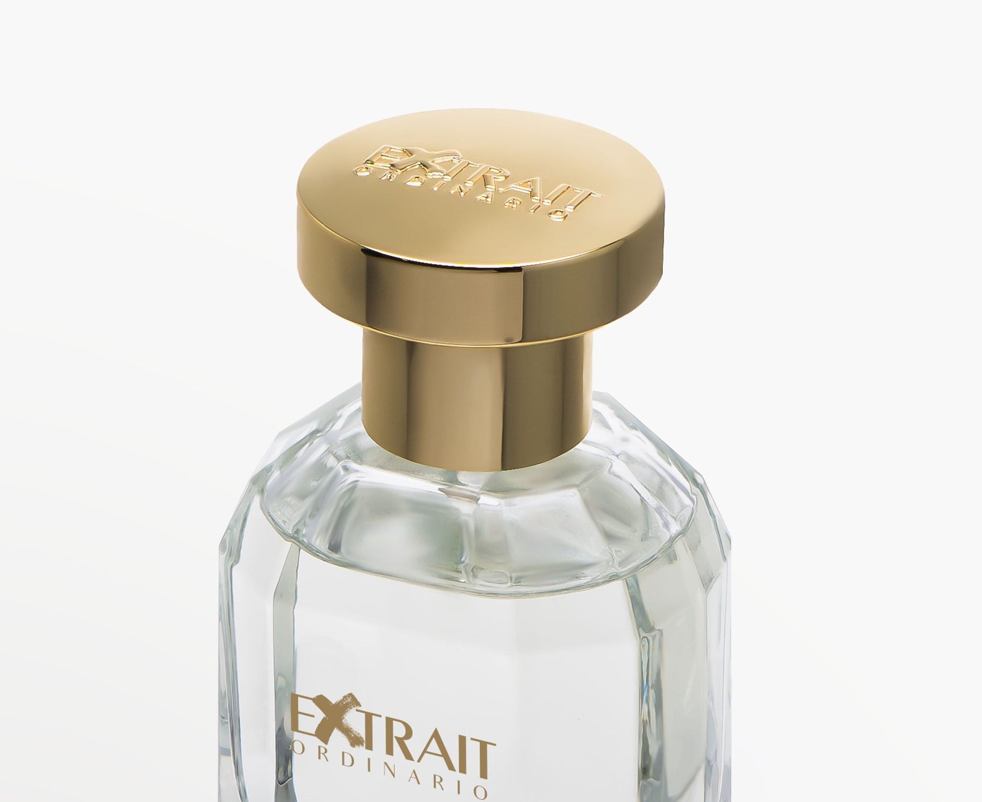 A close-up of the clear glass Sweet Bubble - Extrait Ordinario perfume bottle by Extrait Ordinario, featuring a shiny gold cap and labeled "EXTRAIT," hints at its fruity floral scent against a plain white background.