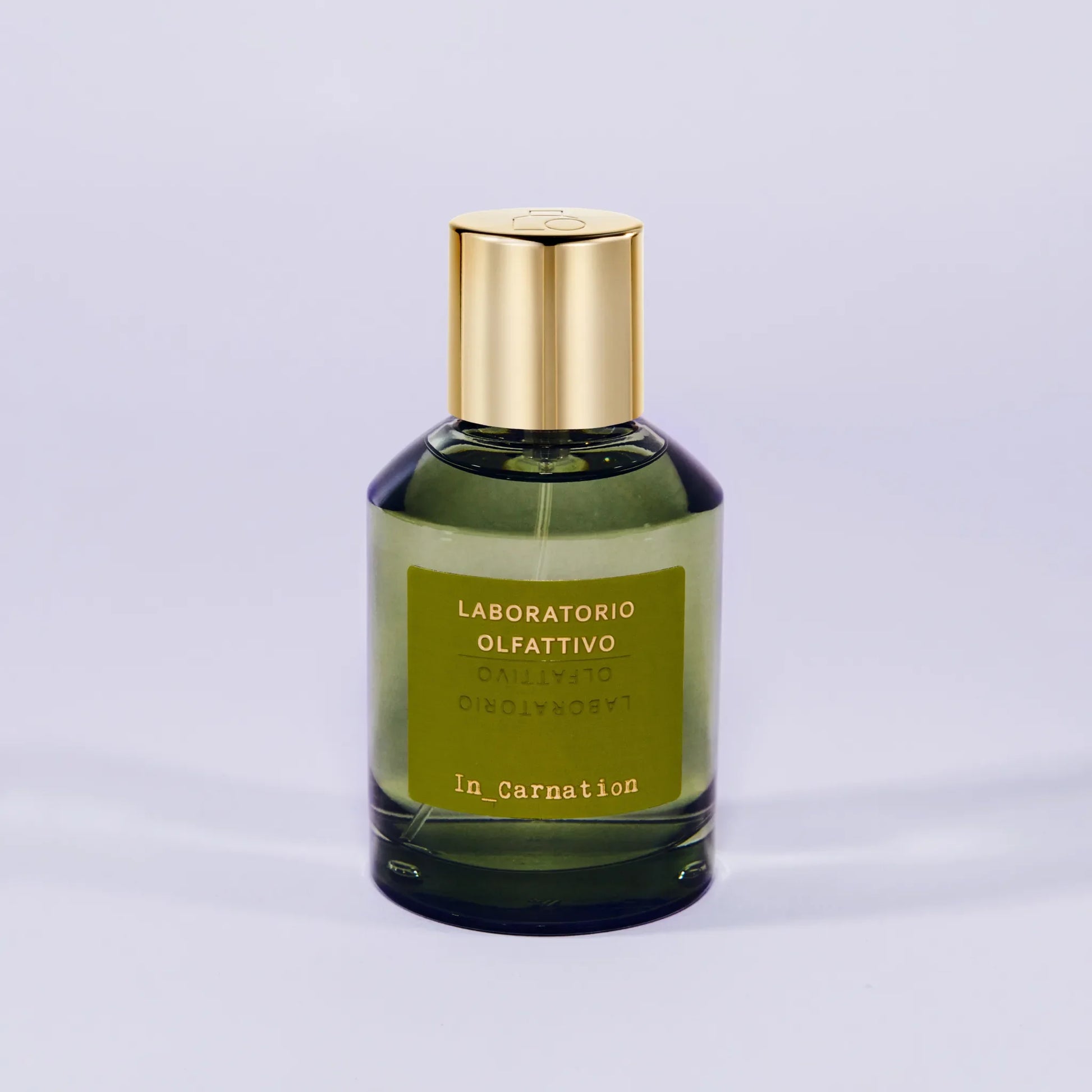 'In_Carnation Laboratorio Olfattivo'Green perfume bottle with gold cap on a light gray background