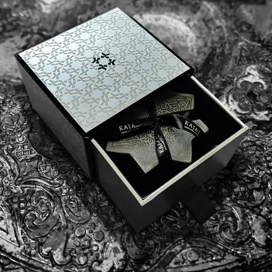 The Kajal Silver Treasure Box Discovery Kit by Kajal Perfumes Paris is a decorative black and silver box with a patterned lid, open to reveal travel-size luxury fragrances—an ideal set for scent enthusiasts.