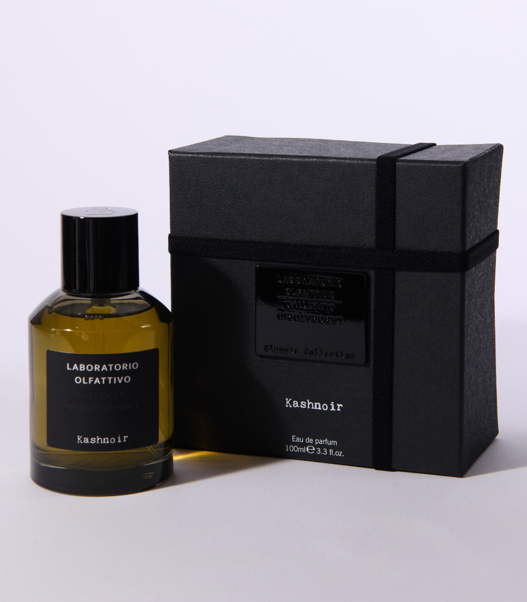 A bottle of Laboratorio Olfattivo Kashnoir stands beside its sleek black box, both adorned with modern black accents that reflect the fragrance’s mysterious character.