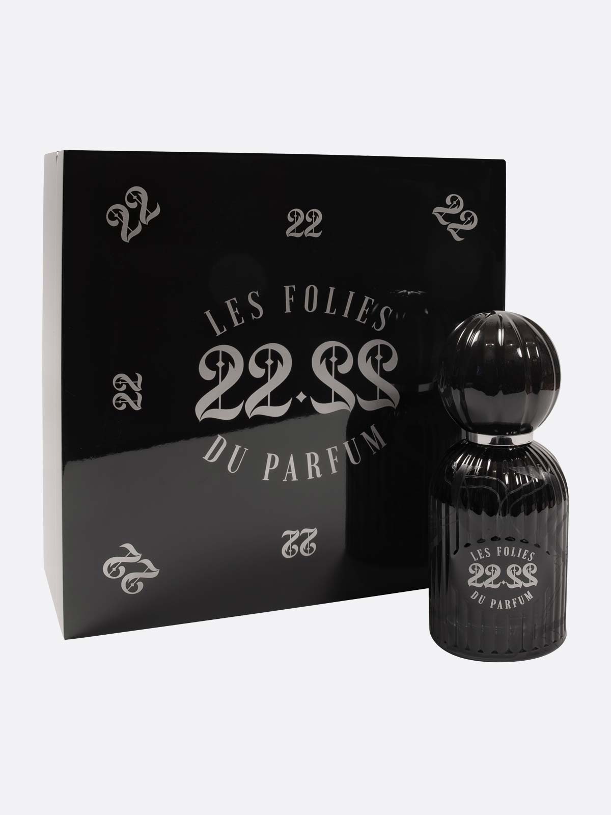 A black Les Folies du Parfum 22.22 bottle stands next to a glossy black box with silver 22 and 22.22 designs, showcasing Italian artistry in handmade perfumes.