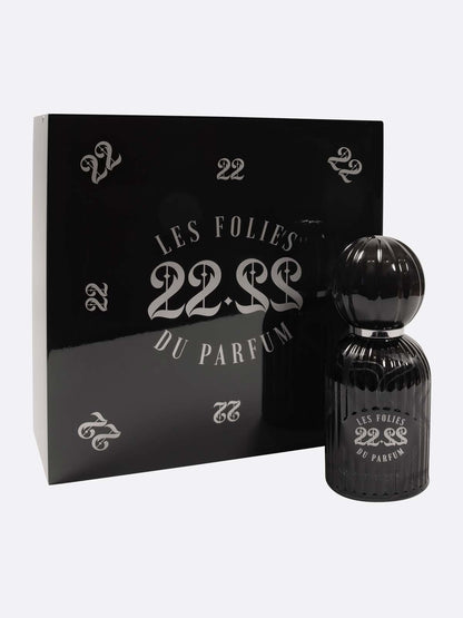 A black Les Folies du Parfum 22.22 bottle stands next to a glossy black box with silver 22 and 22.22 designs, showcasing Italian artistry in handmade perfumes.