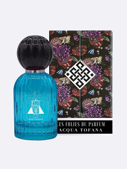 A blue glass bottle of Acqua Tofana - Les Folies du Parfum by Les Folies du Parfum is displayed before its black box, featuring vibrant floral patterns and a bold white logo, hinting at the alluring fragrance inside.