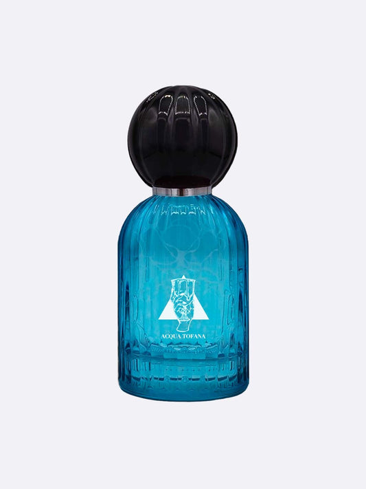 A blue glass perfume bottle with a large round black cap. The front shows a white emblem and “Acqua Tofana - Les Folies du Parfum” by Les Folies du Parfum, evoking a seductive scent. The background is plain and light-colored.