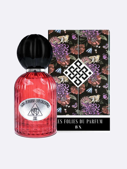 A pink ribbed perfume bottle with a black cap stands before its box decorated with florals, animals, and a geometric logo. The label reads BX - Les Folies du Parfum by Les Folies du Parfum, inspired by the enigmatic Countess of Castiglione.