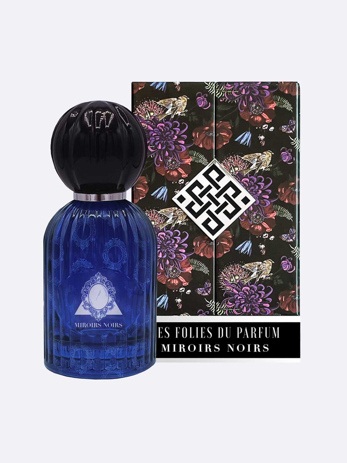 A blue glass Miroirs Noirs - Les Folies du Parfum bottle with a black round cap sits before a black Les Folies du Parfum box decorated with colorful flowers and a white geometric logo. The label reads MIROIRS NOIRS.