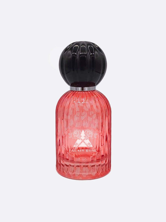 A pink, ribbed glass bottle with a round black cap and embossed design features white text reading "PALAIS ROSE." This Palais Rose - Les Folies du Parfum scent by Les Folies du Parfum evokes Belle Époque elegance. Background is plain white.