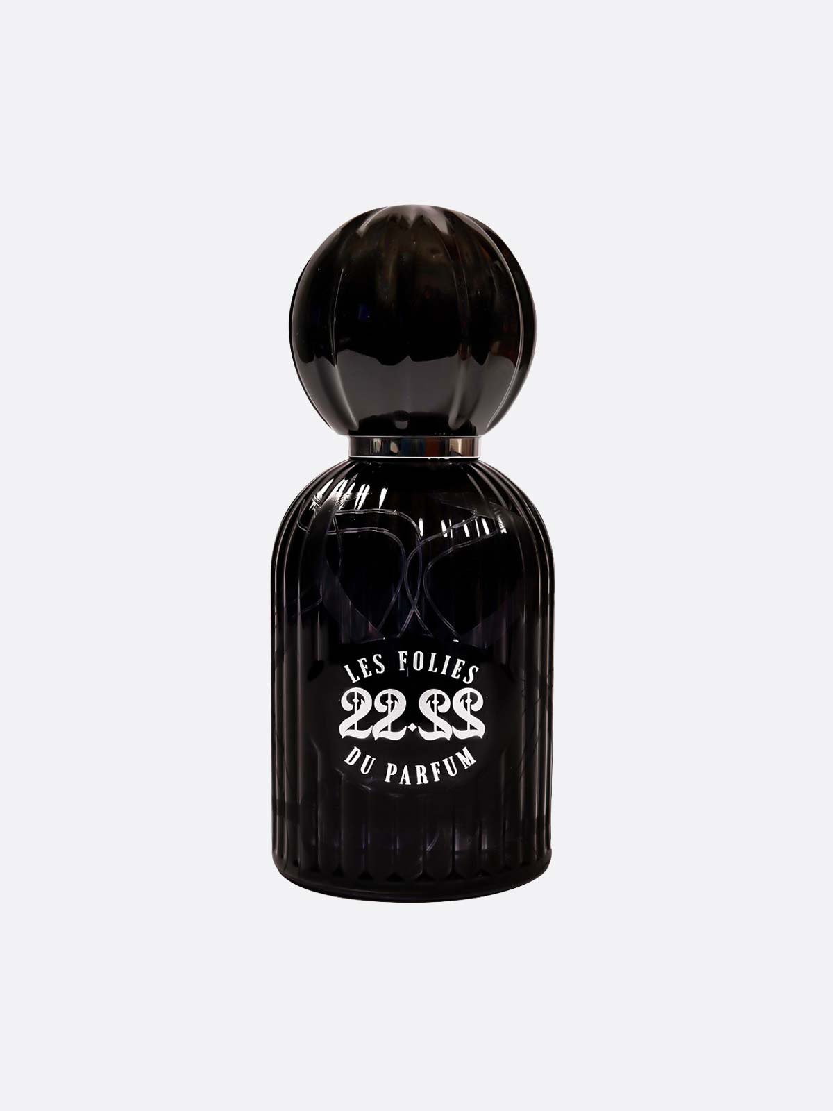 A black, ribbed glass bottle with a rounded cap displays the label "22.22 - Les Folies du Parfum" by Les Folies du Parfum, handmade in Italy, above a white design of three intertwined snakes on a plain light gray background.