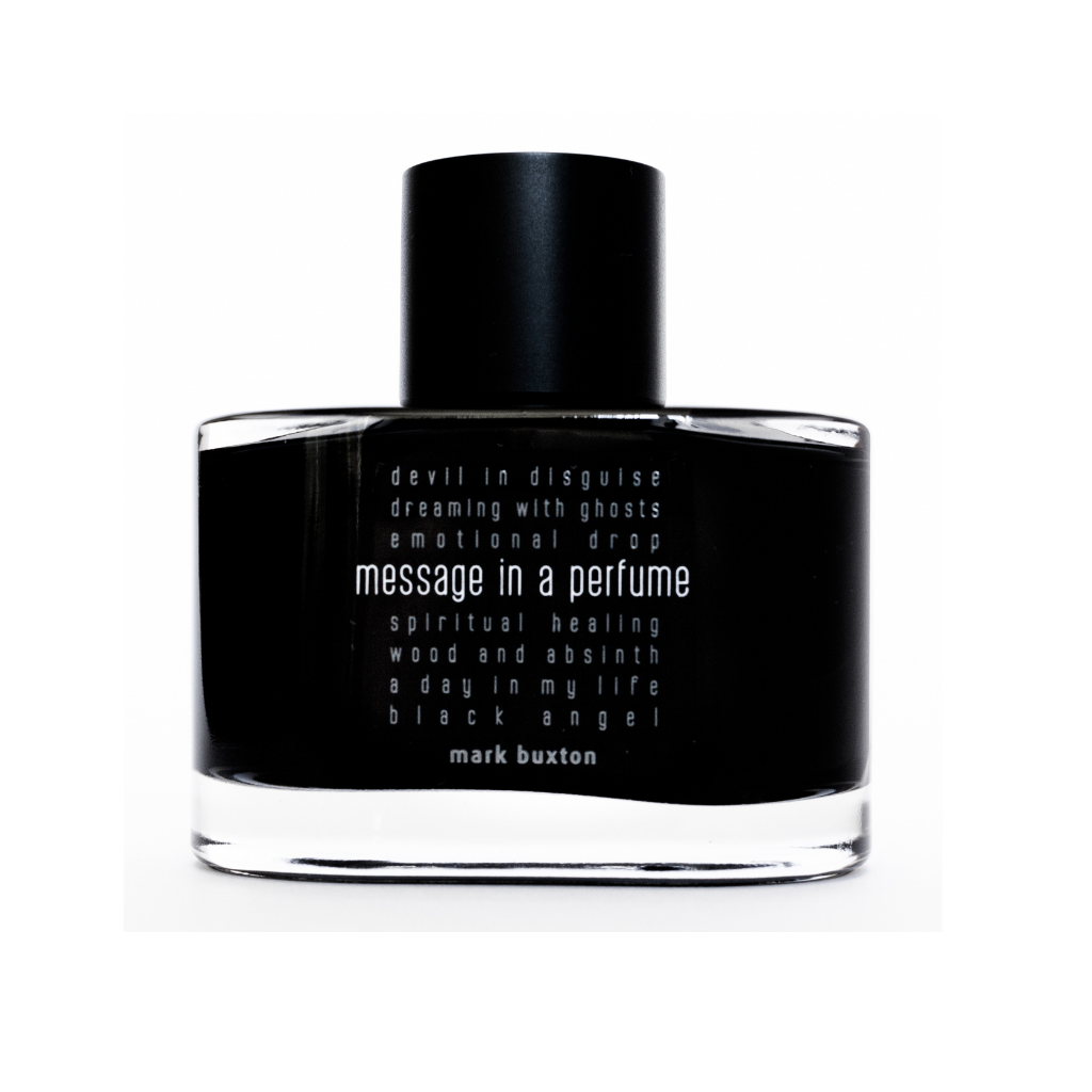 A black bottle of MESSAGE IN A PERFUME Eau de Parfum by Mark Buxton, featuring white text with phrases like devil in disguise, spiritual healing, and a day in my life—an island-inspired fragrance called Paradise.
