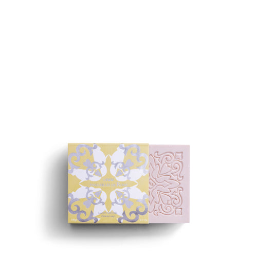The ROSE ET MARIUS SCENTED SOAP by Rose Et Marius is a decorative pink bar with ornate patterns, partially slid out of a pastel yellow and white floral box. Made in France, it features intricate detailing against a white background.