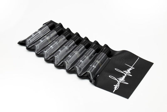 'Filippo Sorcinelli Organ Series'Black and white perfume bottle with cap on a white background.A black silicone roll-up pouch containing eight clear plastic cartridge pens with black caps, shown on a clean white background. The pouch features a white graphic logo on the end.