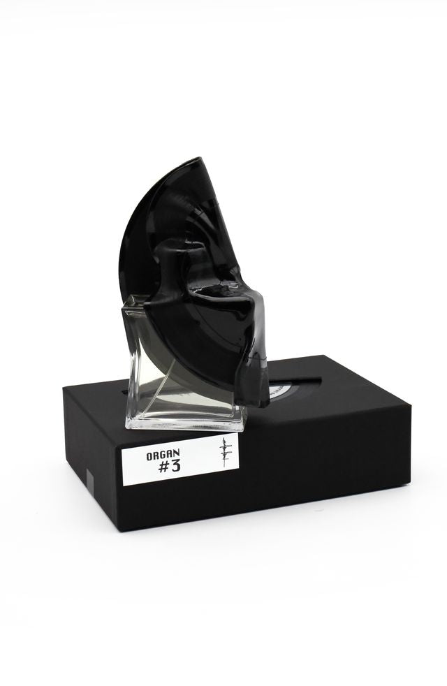 'Filippo Sorcinelli Organ #3'Black and clear ink bottle on a black stand with 'Origin #3' label on a white background