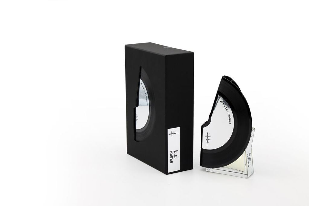 'Filippo Sorcinelli Organ #4'A black semi-circular optical lens or visor displayed next to its black rectangular box on a clear acrylic stand, set against a plain white background.