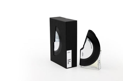 'Filippo Sorcinelli Organ #4'A black semi-circular optical lens or visor displayed next to its black rectangular box on a clear acrylic stand, set against a plain white background.