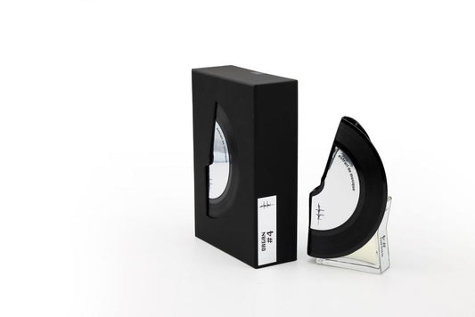 'Filippo Sorcinelli Organ #4'A black semi-circular optical lens or visor displayed next to its black rectangular box on a clear acrylic stand, set against a plain white background.