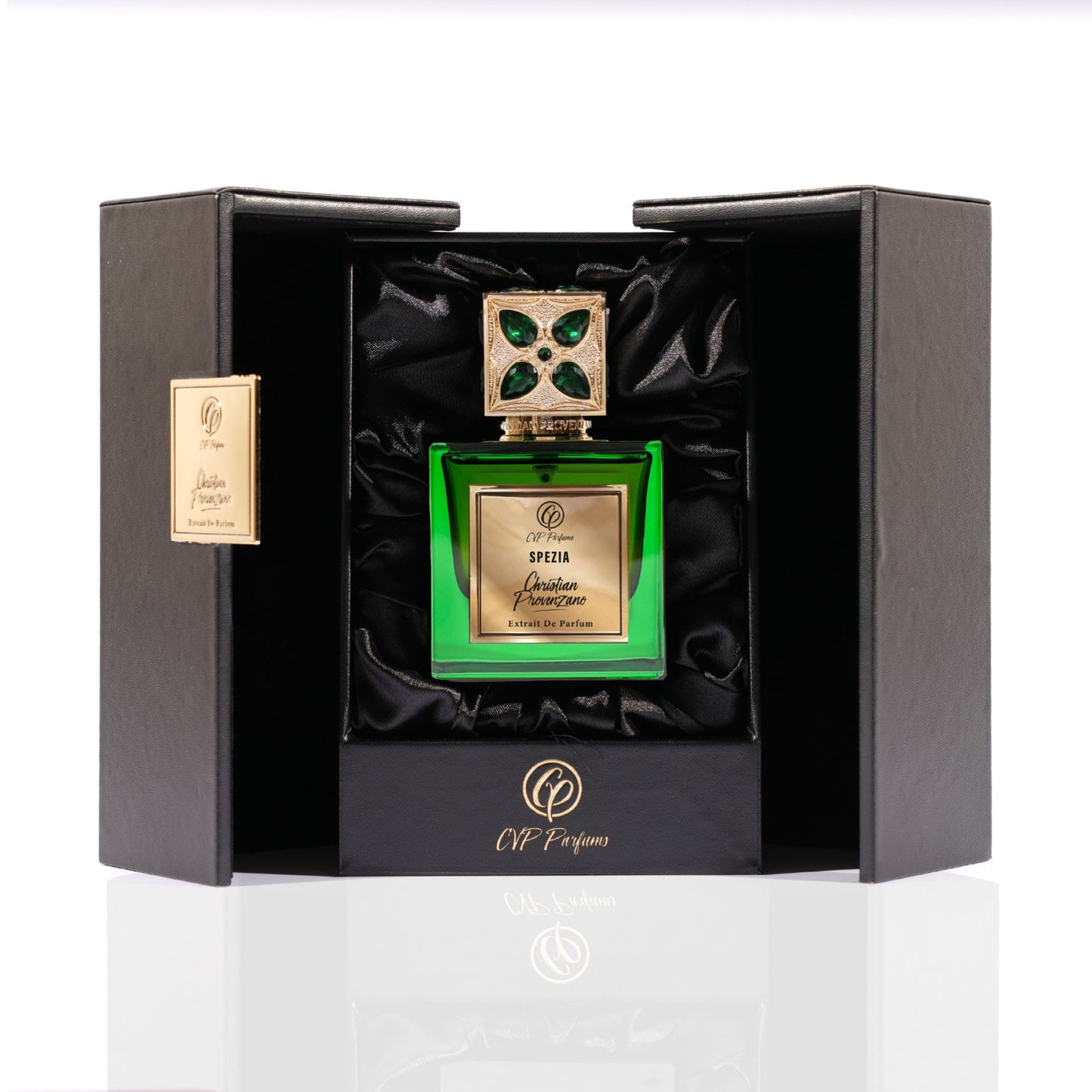 A luxurious green bottle of Spezia Eau de Parfum by Christian Provenzano, with woody notes, features a jeweled cap and rests in an elegant black satin-lined box with gold accents and the Christian Provenzano logo.