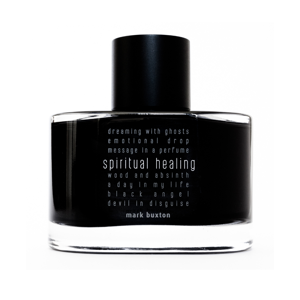 A black unisex SPIRITUAL HEALING Eau de Parfum bottle by Mark Buxton features white text, phrases like "dreaming with ghosts" and "wood and absinth," and notes of osmanthus and blackcurrant buds. The designer’s name appears at the bottom.