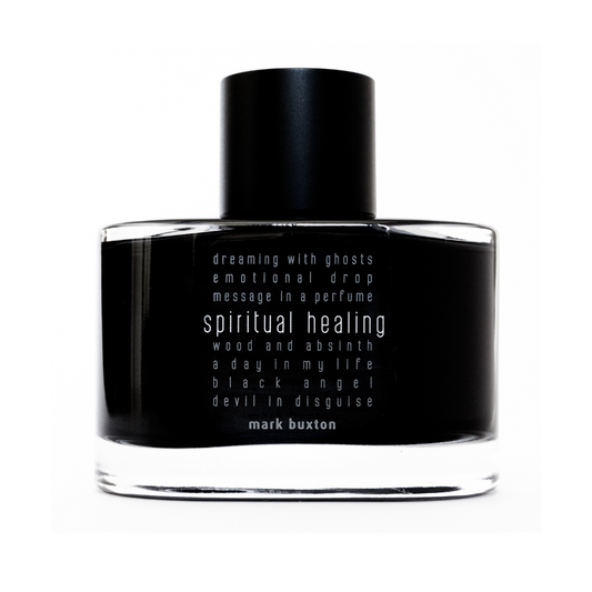 A black unisex SPIRITUAL HEALING Eau de Parfum bottle by Mark Buxton features white text, phrases like "dreaming with ghosts" and "wood and absinth," and notes of osmanthus and blackcurrant buds. The designer’s name appears at the bottom.