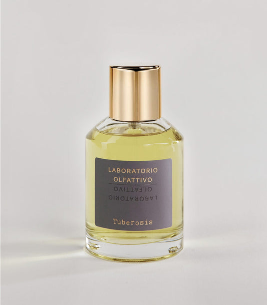 A clear glass bottle with a gold cap and yellow liquid, labeled "Tuberosis - Laboratorio Olfattivo TESTER" in black and gold on gray, sits on a plain white surface. Brand: Laboratorio Olfattivo.