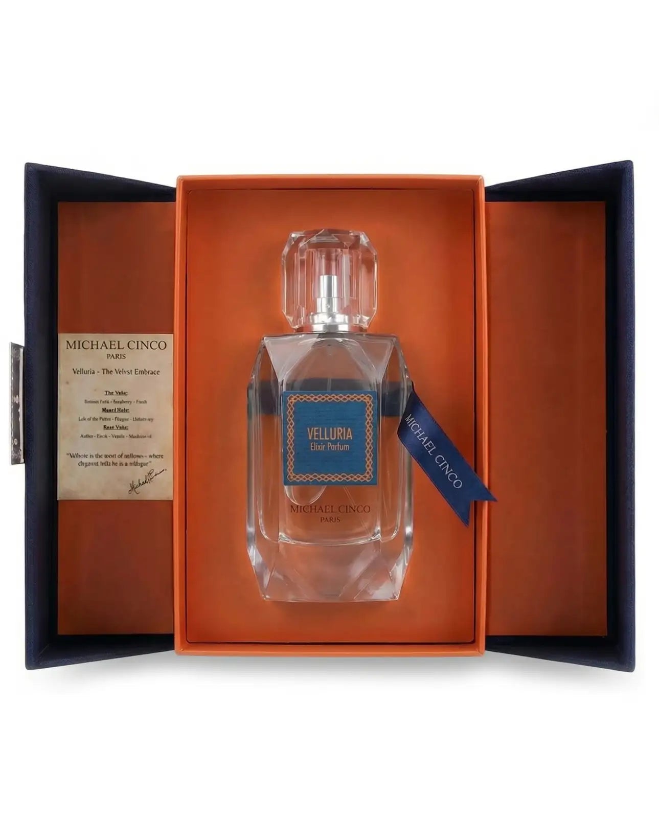 Michael Cinco Velluria Eau de Parfum in a clear glass bottle, presented inside an open orange and navy blue gift box with a brand card on the left.