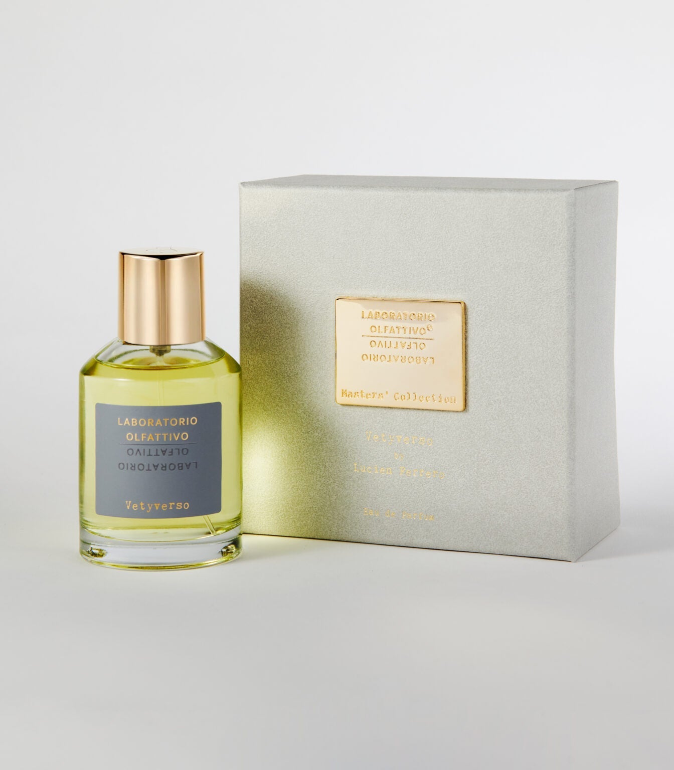 A bottle of Laboratorio Olfattivo Vetyverso perfume with a gold cap is displayed beside its silver-grey box with a gold label. This fragrance features spicy, woody notes, shown against a white background.